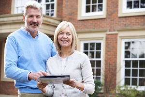 Mature couple standing outside of home